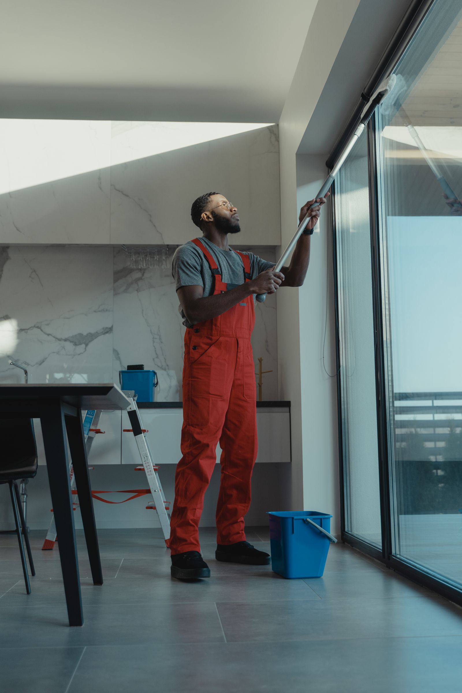A window cleaner cleaning a floor-to-ceiling interior glass wall in a bright modern St. George home