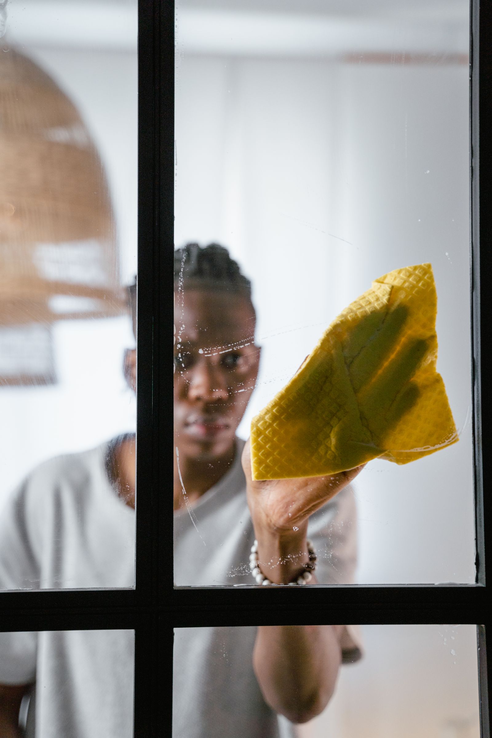 Close detail of a hand wiping a glass pane to a perfectly clear, streak-free finish